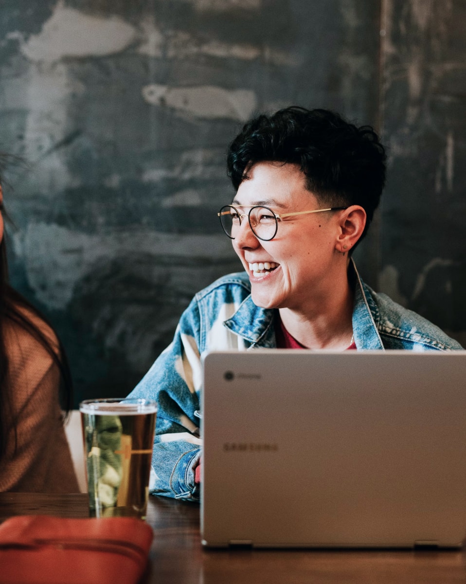 Lady working at laptop and smiling. People, Culture and Careers.