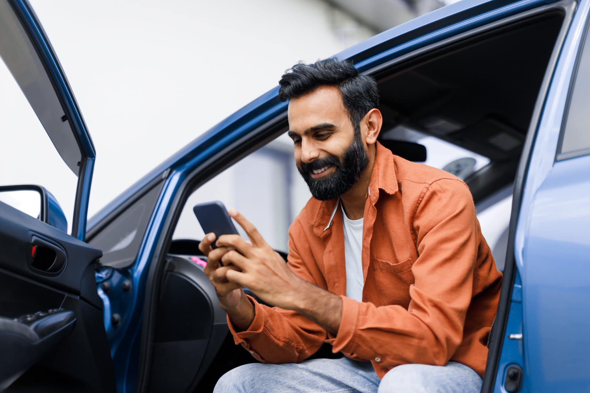 Man Using Phone Sitting In Auto With Opened Door