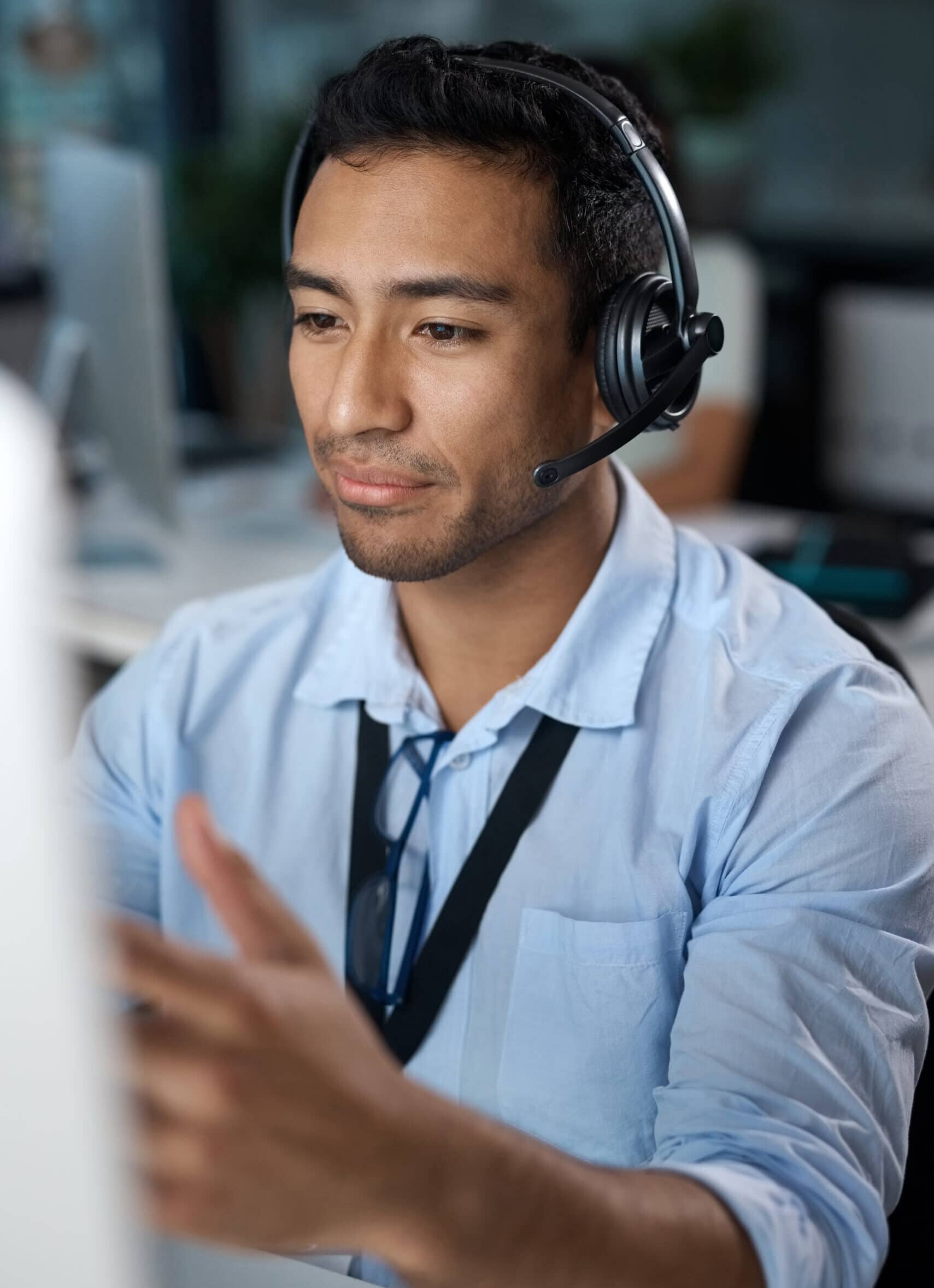 A man in an office in front of his screen wearing a headset.
