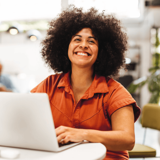 A woman working on her laptop. She is smiling.