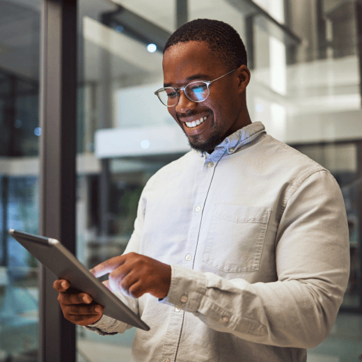 A man standing in an office building looking at a tablet.