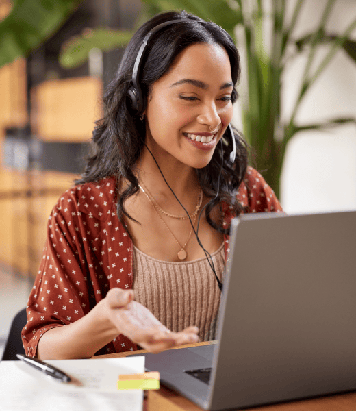 Woman with a headset smiling in front of her laptop.