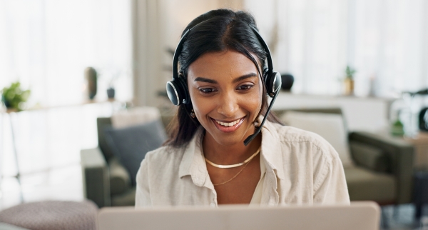 A woman wearing a headset is smiling at a screen