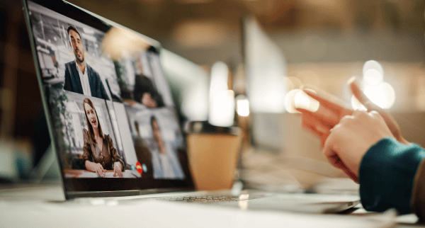 Multiple people in a video meeting. You can see the hands of one person, all other participants are on a tablet screen